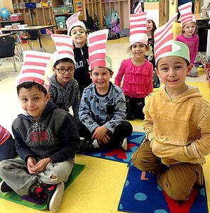 group of students sitting on classroom rug sport paper-made "Cat in the Hat" hats