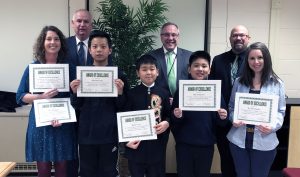 students and teachers holding certificates with members of the Board of Education and administration